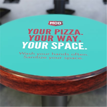 A covering on a MOD stool reads ‘Your pizza. Your way. Your space. Wash your hands often. Sanitize your space.’